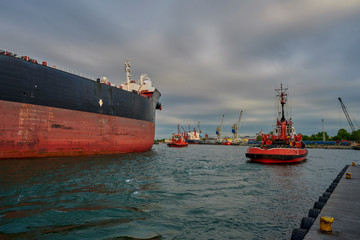 The Port of Gdansk, Gdansk, Poland - a large merchant ship in the tug boats affects the port