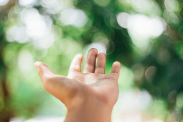 Close up man hand open on green nature bokeh and blur city abstract background. Copy space 