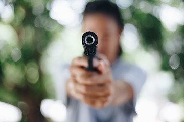 Woman pointing a gun , selective focus on front gun
