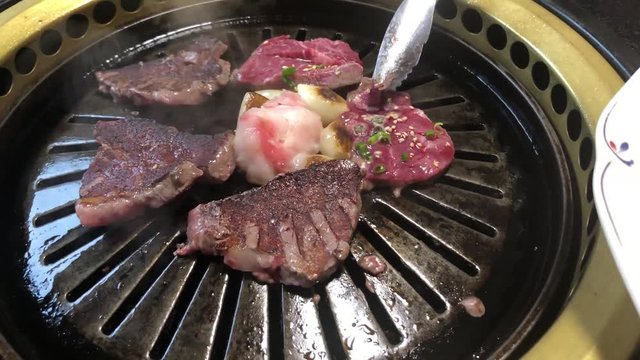 people grilling beef in a japanese style barbecue "yakiniku" 