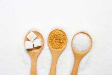 Fototapeta na wymiar Wooden spoon with sugar on white granulated background