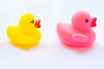 Pink and yellow duck toys on a white