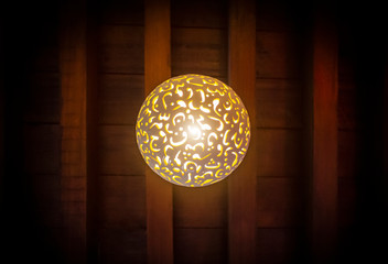 The lamp in the Arab style hangs on the ceiling of a dark room.