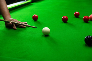 Playing snooker, piercing the red ball, black, aiming the ball and pocketing the hole to score points.