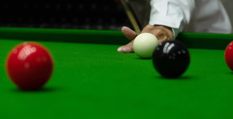 Playing snooker, piercing the red ball, black, aiming the ball and pocketing the hole to score points.