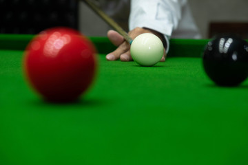 Playing snooker, piercing the red ball, black, aiming the ball and pocketing the hole to score points.