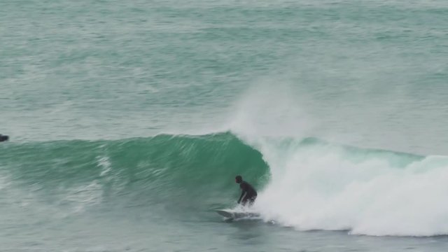 Talented surfer drops in on a large wave in the cold waters off the south coast of Cornwall and performs a layback hack and a cutback on the same swell