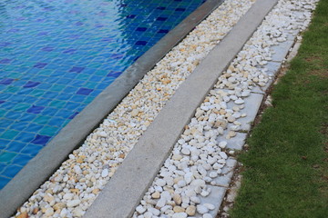 Obraz premium swimming pool grating covered with round white river pebble. drainage system separate lawn and pool covered with white stone. swimming pool drainage system beautiful design.