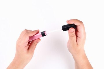 The girl holds in her hand a pink lip gloss on white background. Top view.