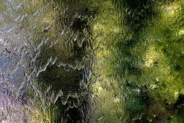 Beautiful blur of falling water stream on a glass mirror wall