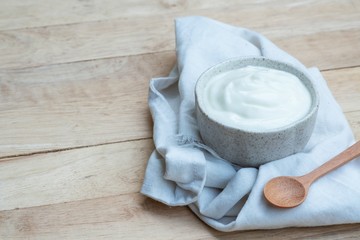 Natural homemade plain organic yogurt in ceramic bowl on wood texture background