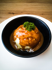 mash potato in a black cup on a white plate and a wooden background.