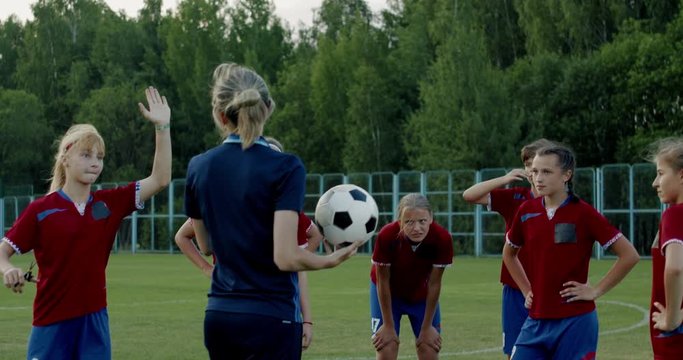Female coach talking to kids during teenager girl soccer football team practice. 4K UHD 60 FPS SLOW MOTION