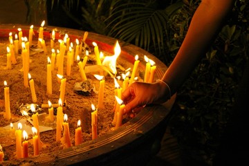 Many candles illuminate in the dark, filmed as blurred
