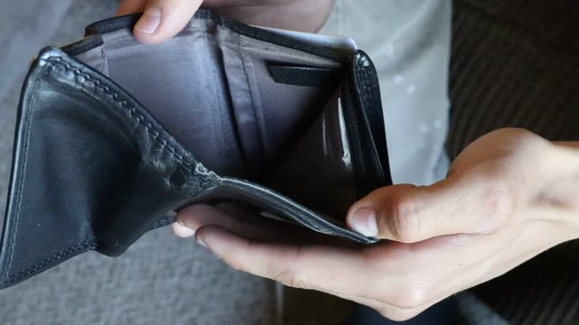 A man opens a wallet and finds out that the wallet has no money in it and is totally empty