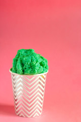 green fruit ice cream or frozen yogurt in stripped   cup on a pink background copy  space