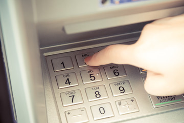 Close up of hand entering pin code at ATM machine