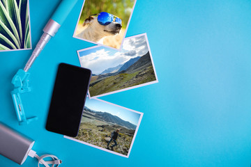 Smartphone with blank screen, flyers and photos on blue background. Mock up, flat lay Summer concept
