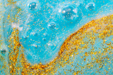 Abstract textured background blue slime with golden glitter particles