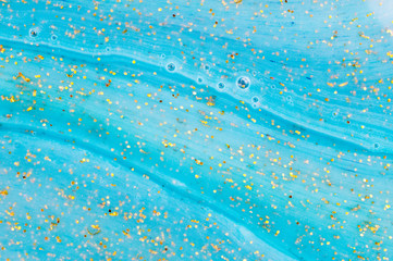 Abstract textured blue background slime with golden glitter. Macro of kids toy slime.