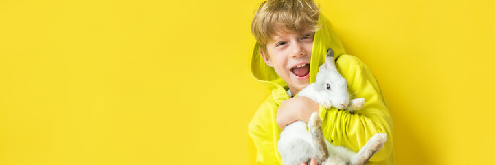 Happy emotional smiling caucasian boy with hand rabbit on hands. Concept yellow on yellow wall....