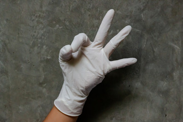 Hand wearing rubber gloves with OK hand sign. A gesture showing the index finger and thumb touching to make an open circle. Represents okay, yes, correct or good.