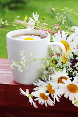 A cup of tea with daisies bouquet