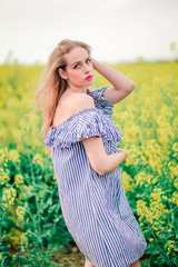 Naklejka na ściany i meble beautiful girl posing for the camera in the rapeseed field