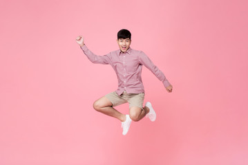 Fototapeta na wymiar Energetic smiling young Asian man in casual clothes jumping