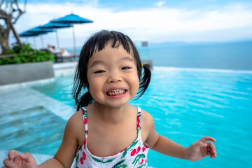 portrait of happy little asian girl playing on the sea, cute smiling