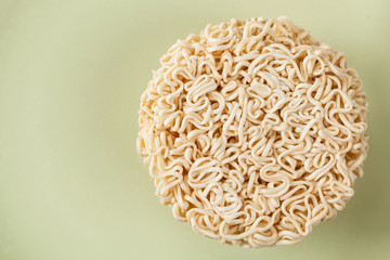 Close up Raw Instant noodles isolated on a green plate with space for copy.