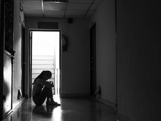 Silhouette of a sad young girl sitting in the darkl, Domestic violence, family problems, Stress, violence, The concept of depression and suicide.