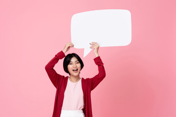 Smiling young Asian woman holding empty speech bubble in pink background