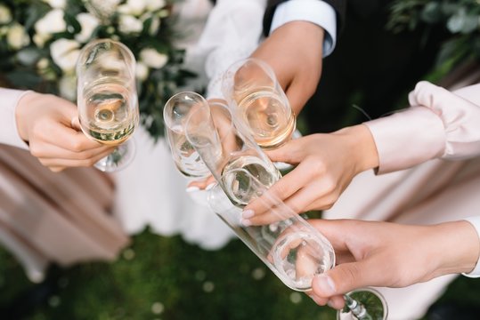 Guests at a wedding with the bride and groom clink glasses of champagne or white wine - Powered by Adobe