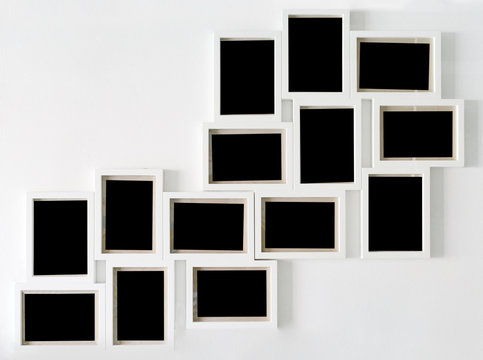 White picture frame and black decorative hanging on white wall
