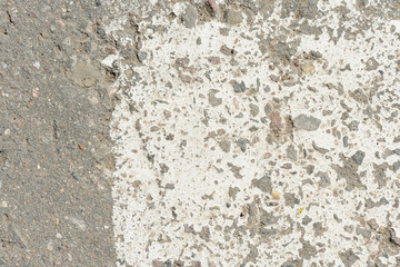 Old asphalt surface with white paint on it close up. Abstract background