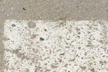 Old asphalt surface with white paint on it close up. Abstract background