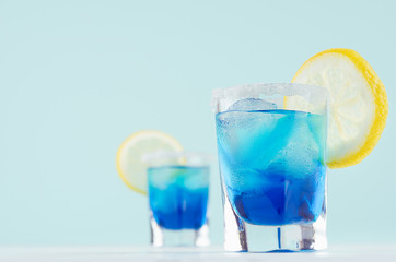 Bright summer fresh blue fruit cocktail with blue curacao liquor, ice cubes, sugar rim, lemon slice...