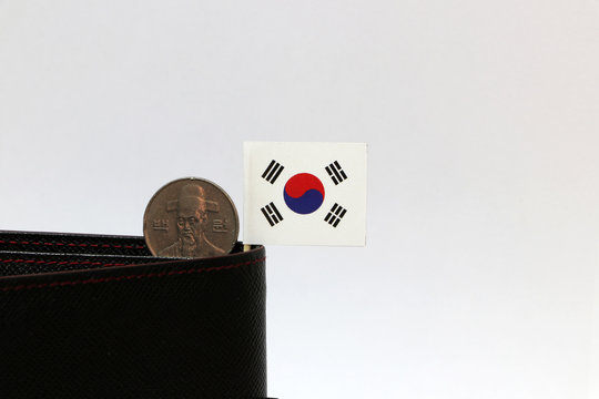One hundred Korean won coin on obverse, (KRW) and mini South Korea flag stick on the black wallet with white background.