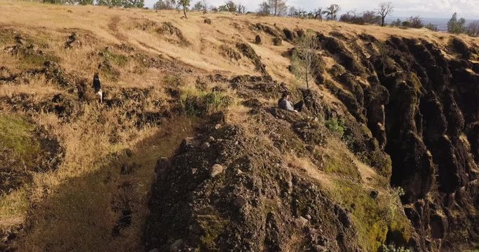 AERIAL: Drone circles one man and his dog (German Shepherd) at the top of a canyon in Chico, California (Butte Country)