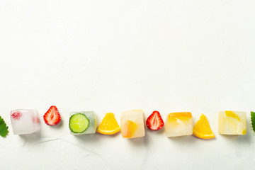 Ice cubes with fruit and mint leaves on a white stone background. Fruit ice concept, quenching...