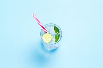 Glass of cold and refreshing water with ice, mint and cucumber on a blue background. Ice Cube. Concept of hot summer, alcohol, cooling drink, thirst quenching, bar. Flat lay, top view