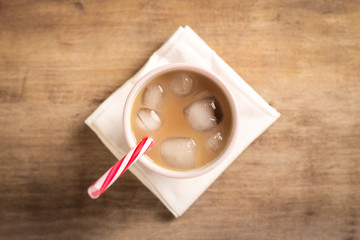 Refreshing and bracing iced coffee in a glass on a wooden background. Concept coffee shop, quenching thirst, summer. Flat lay, top view