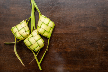 Ketupat Pouches on Wooden Background - Ketupat is a type of dumpling made from rice packed inside a diamond-shaped container of woven palm leaf pouch.