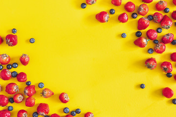 Strawberry and blueberry on yellow background. Flat lay, top view