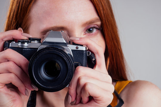 Photographer in a yellow shirt with her camera on white background studio.