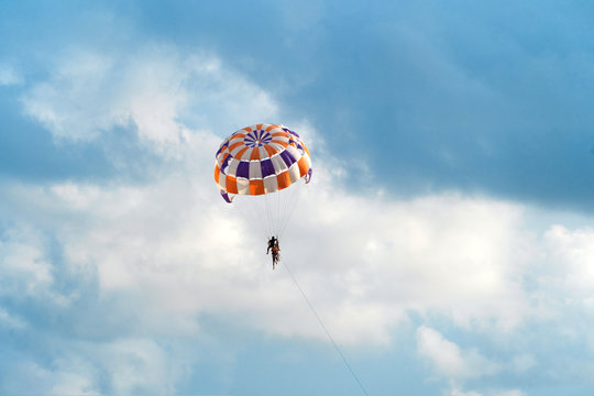 People flying in a colorful parachute or parasail together with blue sky and clouds in freedom and travel concept.