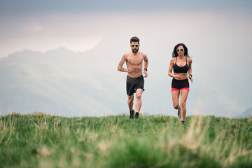 Sporty man and woman run hot in the summer on hill meadows