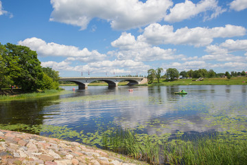 Fototapeta na wymiar City Jelgava, Latvian Republic. River Lielupe, people are driving catamaran. Bridge and water. Jun 9. 2019. Travel photo.