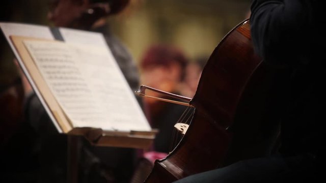 Close up footage of a person performing on a cello during a concert.